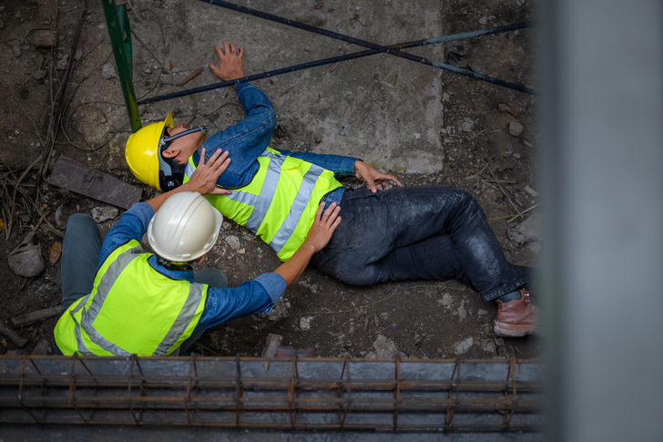 A young Asian builder falls from a scaffold at a construction site. An engineer supervising the construction came to the aid of a construction worker who fell from a height with hip and leg injuries. - © VR Studio - stock.adobe.com
