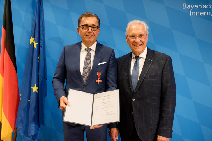 Michael Hilpert und Staatsminister Herrmann präsentieren die von Bundespräsident Steinmeier unterschriebene Verleihungsurkunde