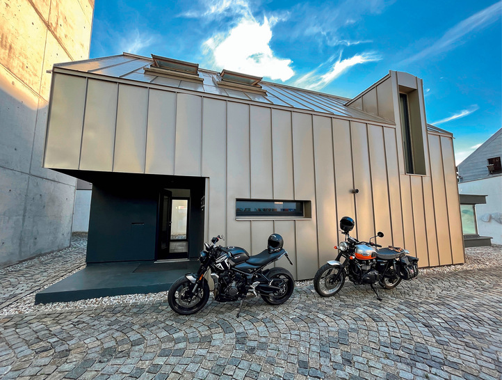 Auf eine Dachrinne wurde bewusst verzichtet. Stattdessen wird anfallendes Niederschlagswasser über ein Abtropf­profil in den Kiesbereich am Gebäudesockel geleitet