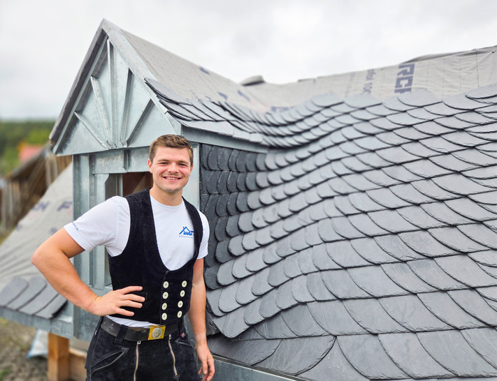 Noah Jakubowski vor einer mit Metall bekleideten Gaubenfront in einem Schieferdach