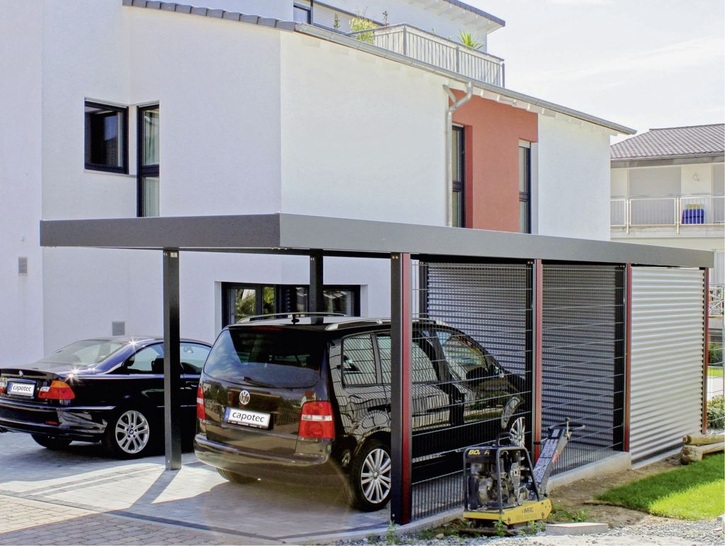 Das Carportdesign wirkt durch den fließenden Farbübergang vom Wohnhaus harmonisch. Moderne Wellprofile am Geräteraum unterstreichen die zeitgemäße Hausarchitektur. ­ Eingerückte ­Stützen sowie eine Stabgitterverkleidung vermitteln zusätzlich eine dezente und luftig-leichte Gesamtoptik