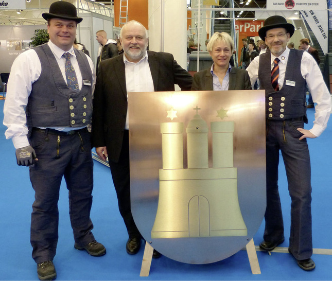 Alexander Schade (r.) und Andreas Witt (l.) freuen sich über das Hamburger Stadtwappen aus MKM-Kupfer. Angela Zeng und Stefan Quandt (beide MKM — Mannsfelder Kupfer und Messing GmbH in Hettstedt) hatten es mit zur GET Nord gebracht — inzwischen schmückt es ein Innungsgebäude des Fachverbandes Sanitär Heizung Klempner Hamburg
