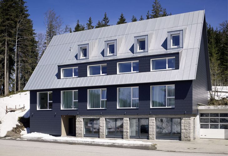 Das neue Gästehaus der Feldbergklinik orientiert sich in der Größe an einem Vorgängerbau, erweist sich aber mit seiner Formensprache und Ausstattung eindeutig als modernes Gebäude. Auf eine Dachentwässerung wurde wegen des starken Schneefalls ebenso verzichtet wie auf Schneefänge