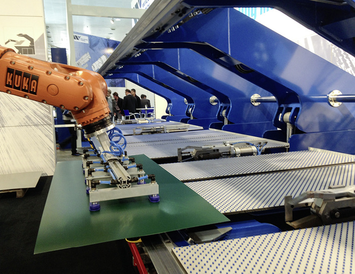 Ein Roboter bestückt den Variobend-Doppelbieger und entnimmt das fertige Profil nach dem Biegevorgang
