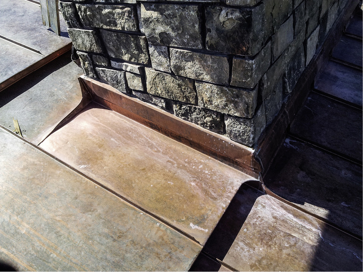 
Die Abdichtungen mit Kupferprofilen am Fuß der Rauchabzüge aus der Nähe



