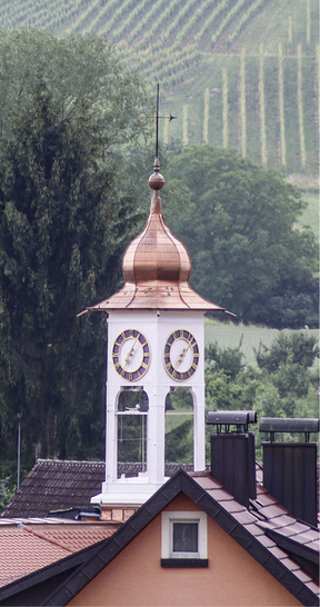 



Umrahmt von sanften Hügeln und Weinbergen liegt Vögisheim im Markgräflerland. Der neu eingedeckte Glockenturm des Gemeindesaals überragt die Dächer

