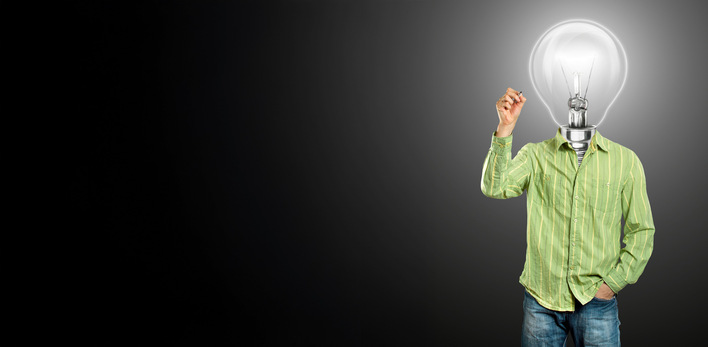 „Einzelperson in grüner Arbeitskleidung mit einer Glühbirne als Kopf symbolisiert kreative Ideen und Innovationen im Bereich der Gebäudetechnik, vor dunklem Hintergrund. - © leedsn - stock.adobe.com