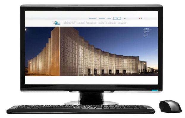 „Computerbildschirm zeigt eine Webseite mit aktuellen Architekturtrends, im Vordergrund Tastatur und Maus für Fachbetriebe der Spengler-, Klempner- und Dachdeckerbranche.“. - © System Arquitectura /  https://elzinc.es/de/