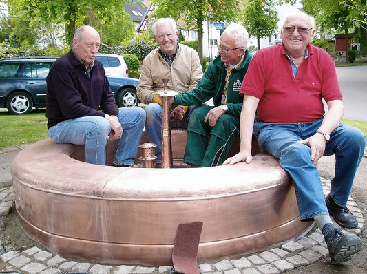 Stolz präsentieren die frisch gebackenen „Kupferschmiede-Gesellen“ um Kupferschmiedemeister Gottlieb Dangel (r.)das neue, aus Kupfer gefertigte Brunnenbecken
